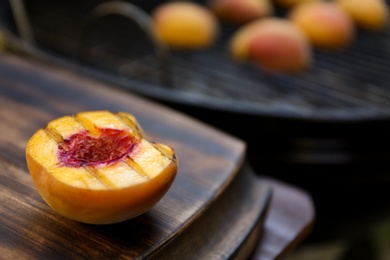 Photo of Half of delicious grilled peach on wooden table, closeup