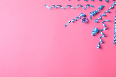 Photo of Light blue serpentine streamers on pink background, flat lay. Space for text