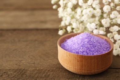 Purple sea salt and beautiful flowers on wooden table, closeup. Space for text