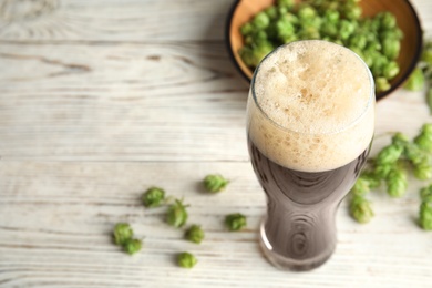 Photo of Composition with tasty beer and fresh green hops on wooden table. Space for text