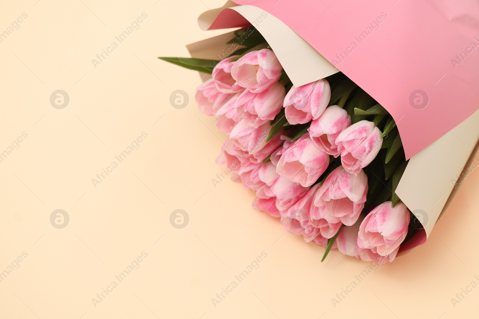 Photo of Beautiful bouquet of fresh pink tulips on beige background, top view. Space for text