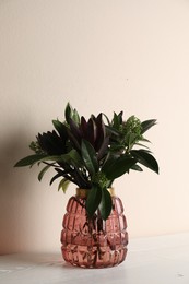 Photo of Vase with beautiful bouquet on white wooden table near beige wall