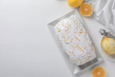 Photo of Tasty lemon cake with glaze and citrus fruits on white wooden table, flat lay. Space for text