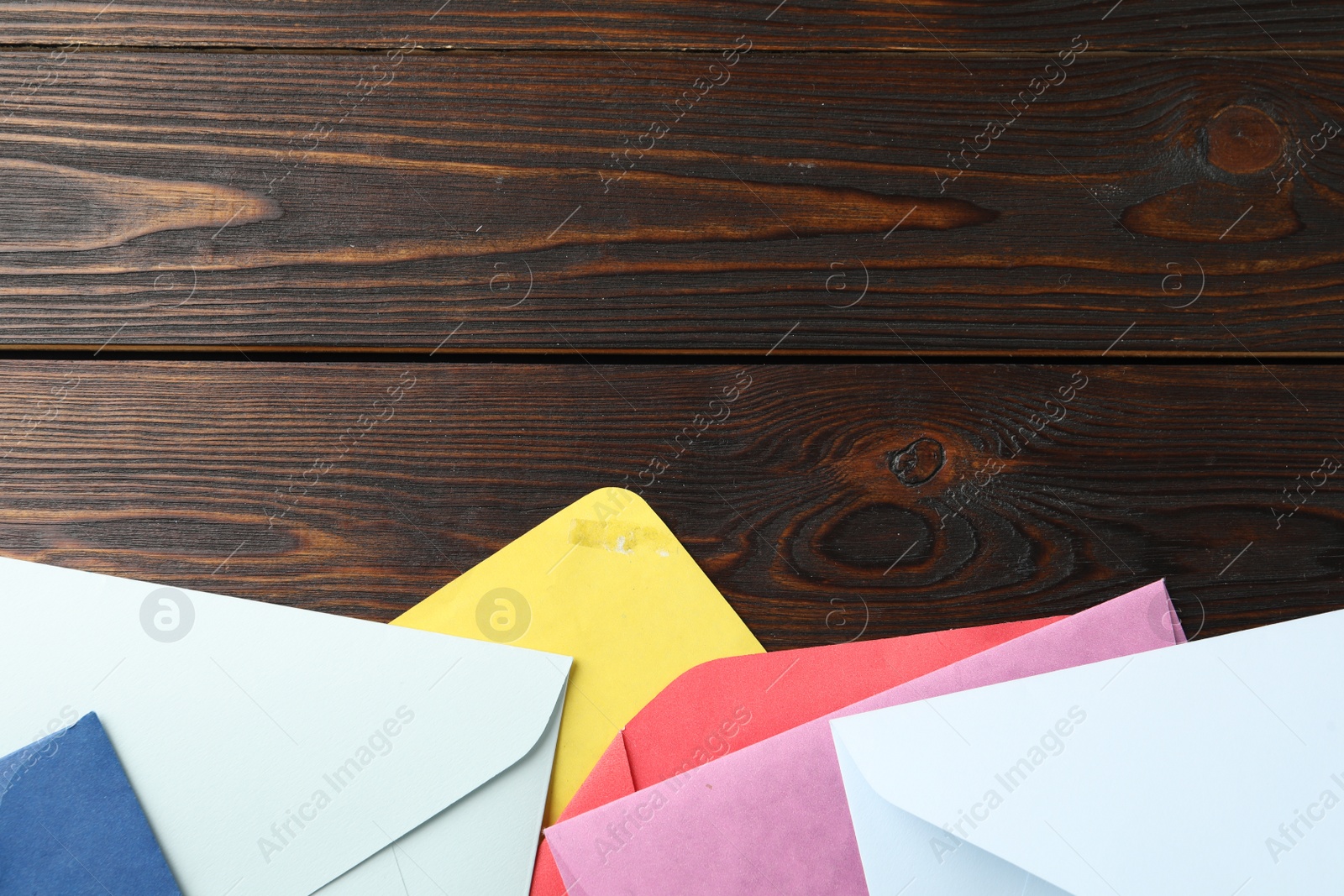 Photo of Colorful paper envelopes on wooden background, flat lay. Space for text