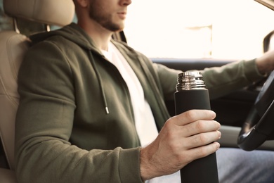 Man with thermos driving car, closeup view