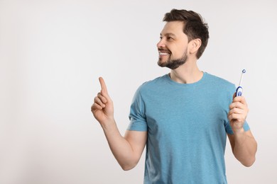 Happy man holding electric toothbrush on white background. Space for text