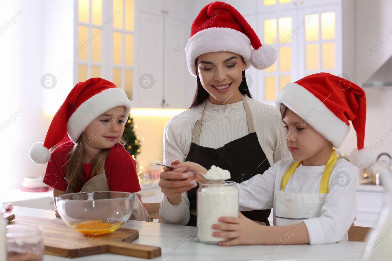 Photo of Mother with her cute little children making Christmas cookies in kitchen