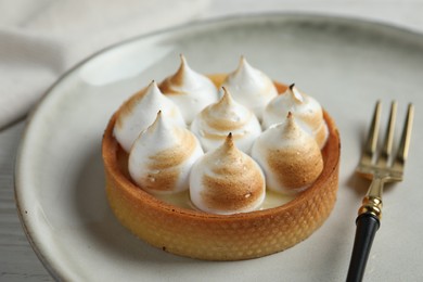 Photo of Tartlet with meringue on white table, closeup. Delicious dessert