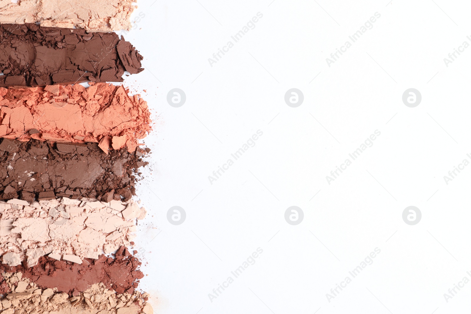 Photo of Swatches of crushed eye shadows on white background, top view. Space for text