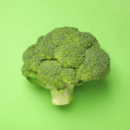 Photo of Fresh broccoli on green background, top view