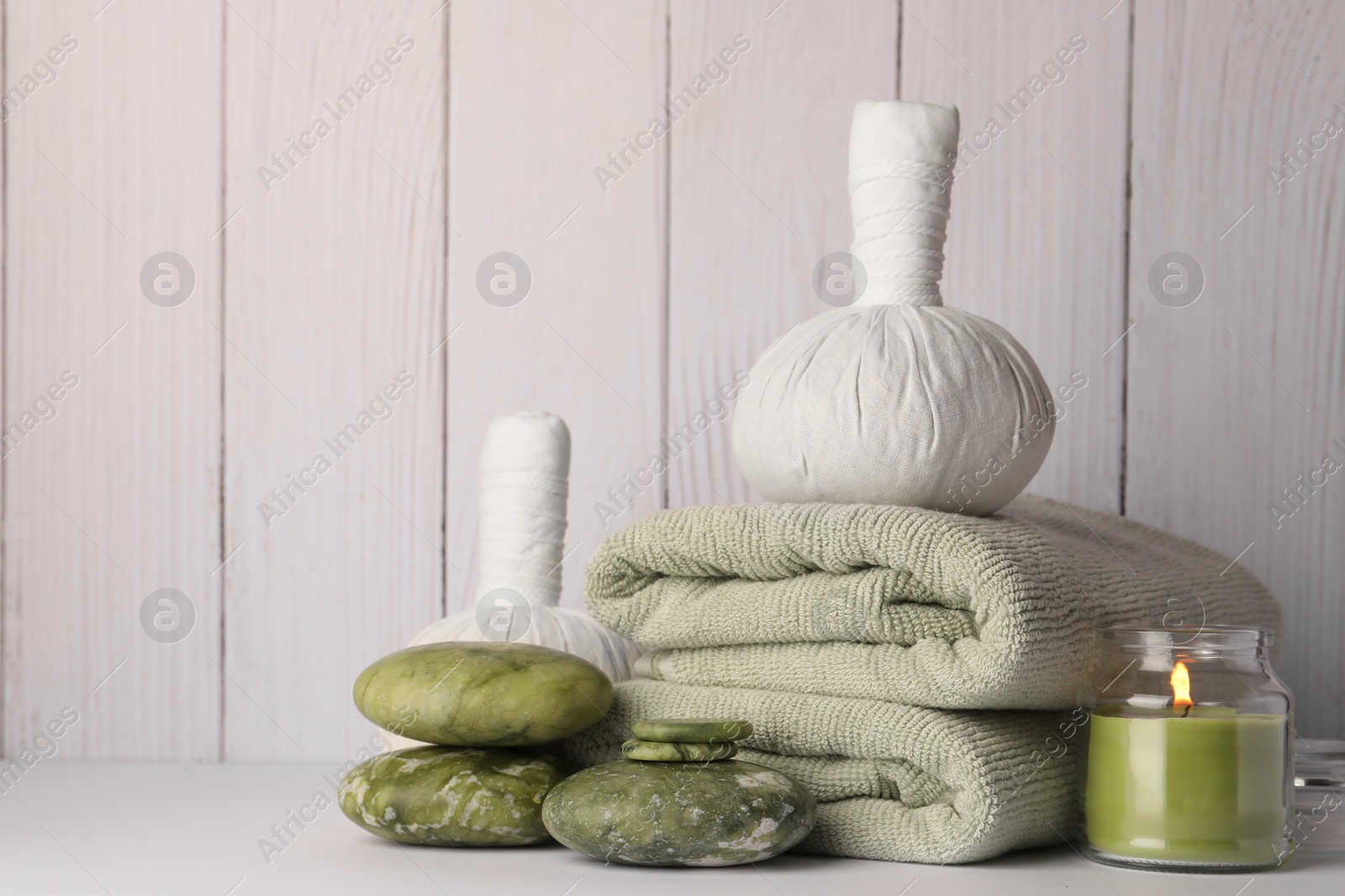 Photo of Composition with different spa products and candle on white table against wooden background. Space for text