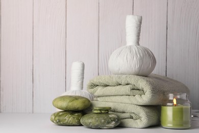 Composition with different spa products and candle on white table against wooden background. Space for text