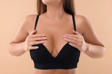 Woman with beautiful breast on beige background, closeup