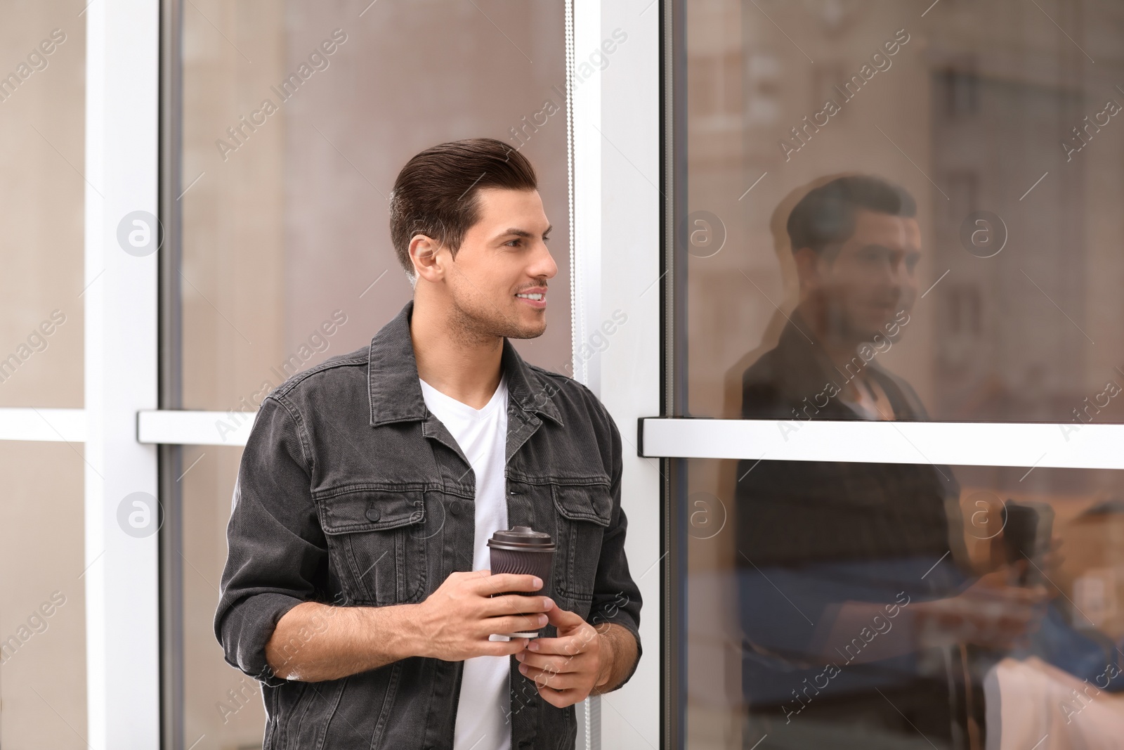Photo of Handsome man with cup of coffee near window