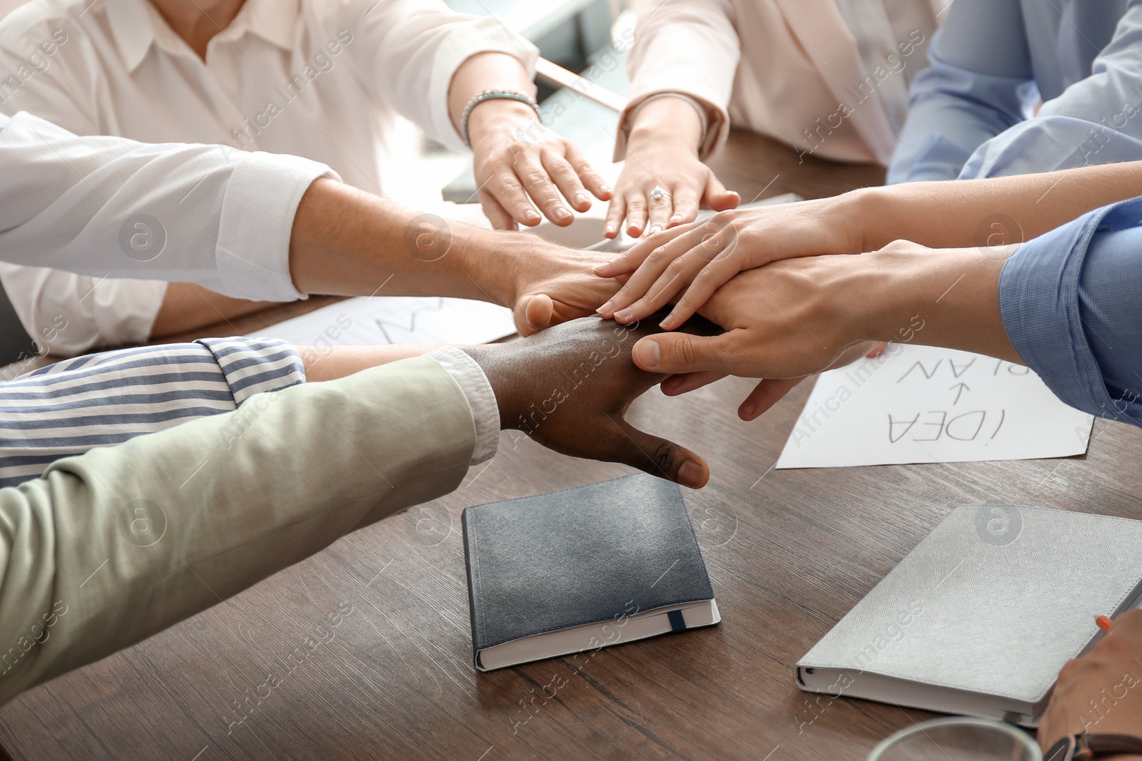 Photo of People putting hands together at table. Unity concept