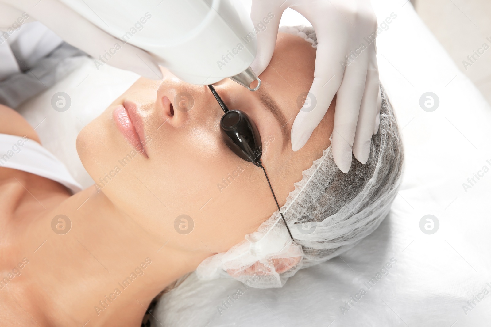 Photo of Young woman undergoing laser removal of permanent makeup in salon. Eyebrow correction