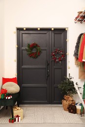 Photo of Christmas wreaths hanging on wooden door and festive decoration indoors