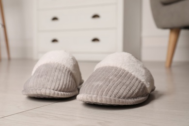 Grey warm slippers on floor in room