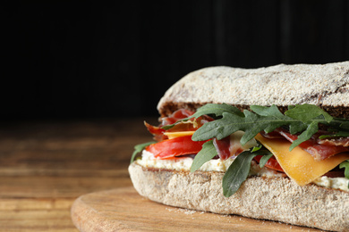 Photo of Delicious sandwich with fresh vegetables and prosciutto on wooden table, closeup. Space for text