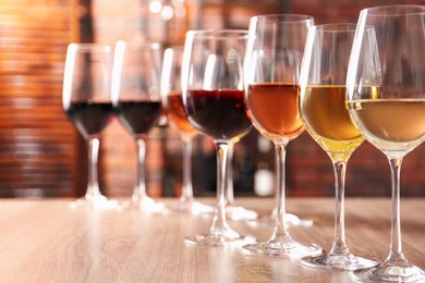 Different tasty wines in glasses on wooden table, space for text