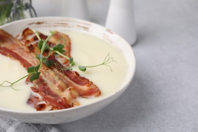 Photo of Delicious potato soup with bacon and microgreens on grey table, closeup. Space for text