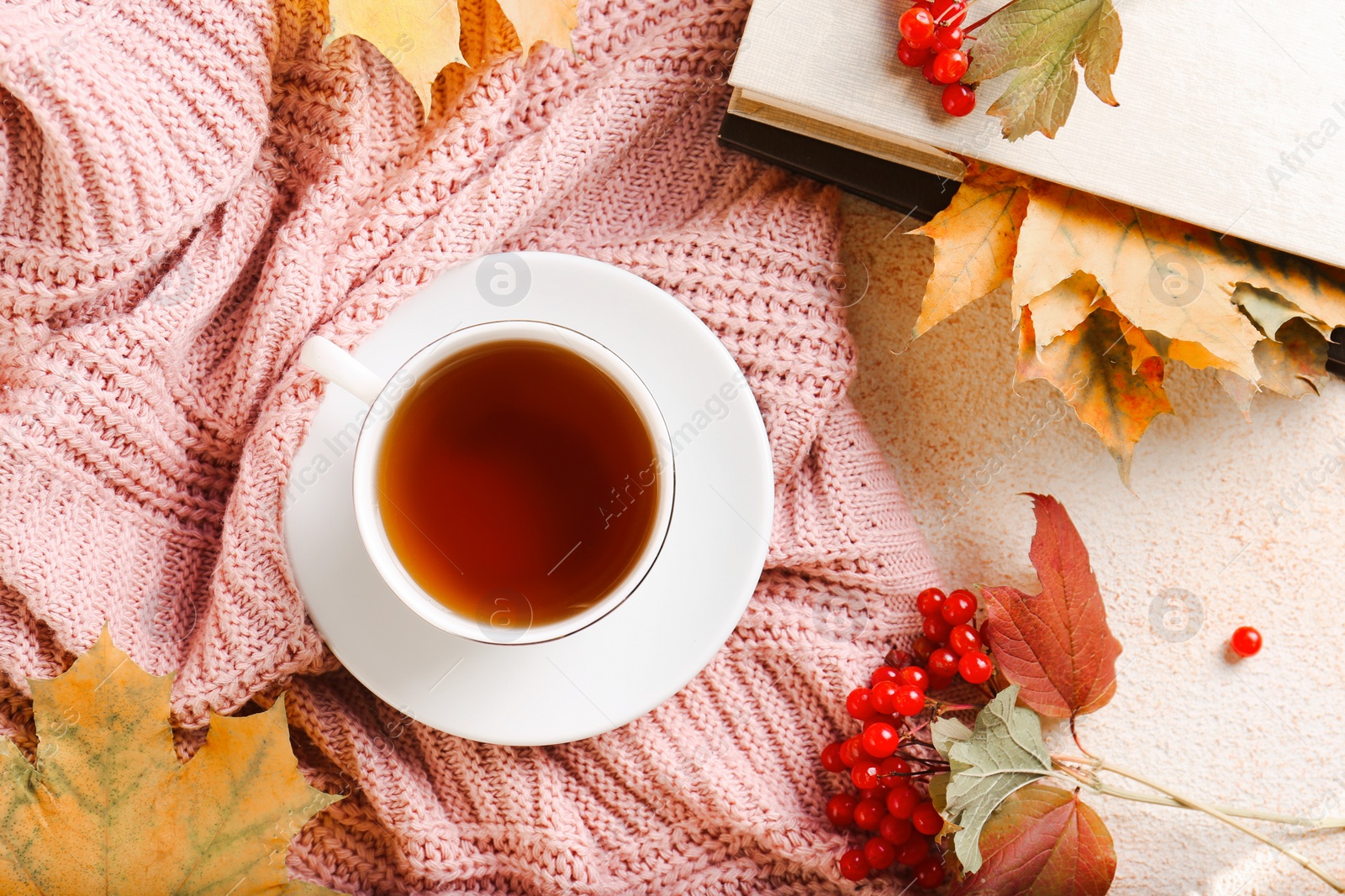 Photo of Flat lay composition with cup of aromatic tea and soft pink sweater on beige textured table. Autumn atmosphere