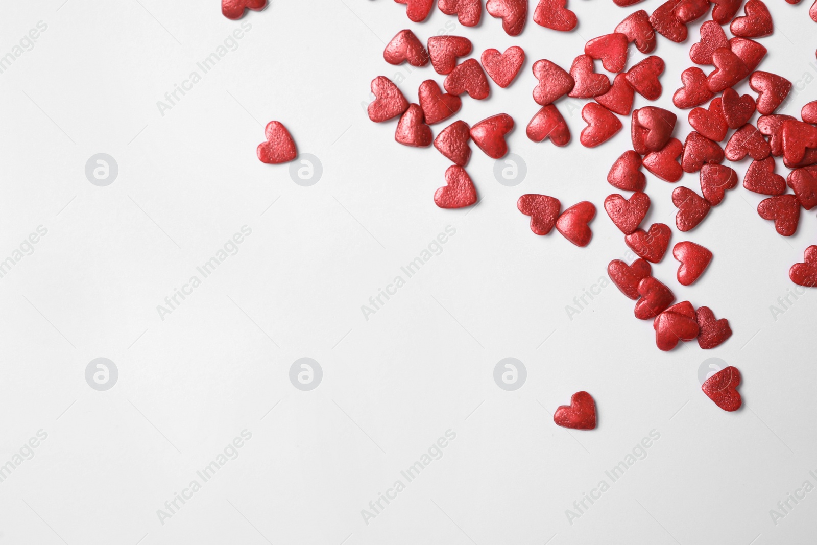 Photo of Bright heart shaped sprinkles on white background, top view