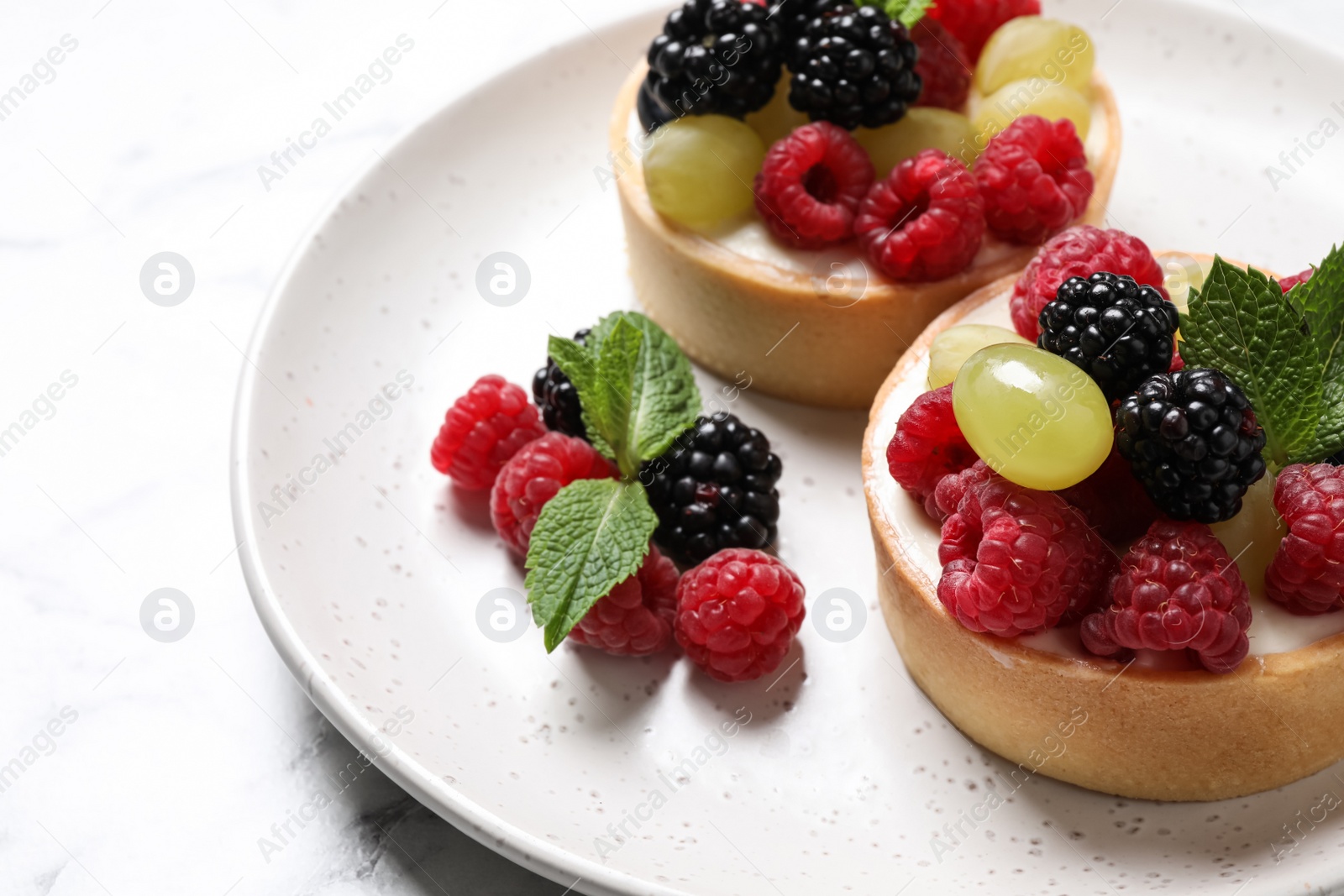 Photo of Delicious tartlets with berries on table, closeup