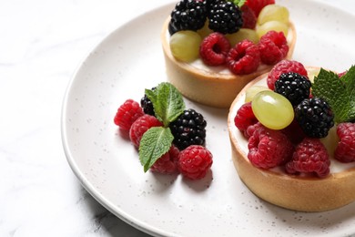 Delicious tartlets with berries on table, closeup