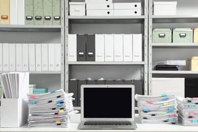 Photo of Laptop and documents on desk in office. Space for text