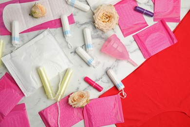 Photo of Tampons and other menstrual hygienic products on white marble background, flat lay