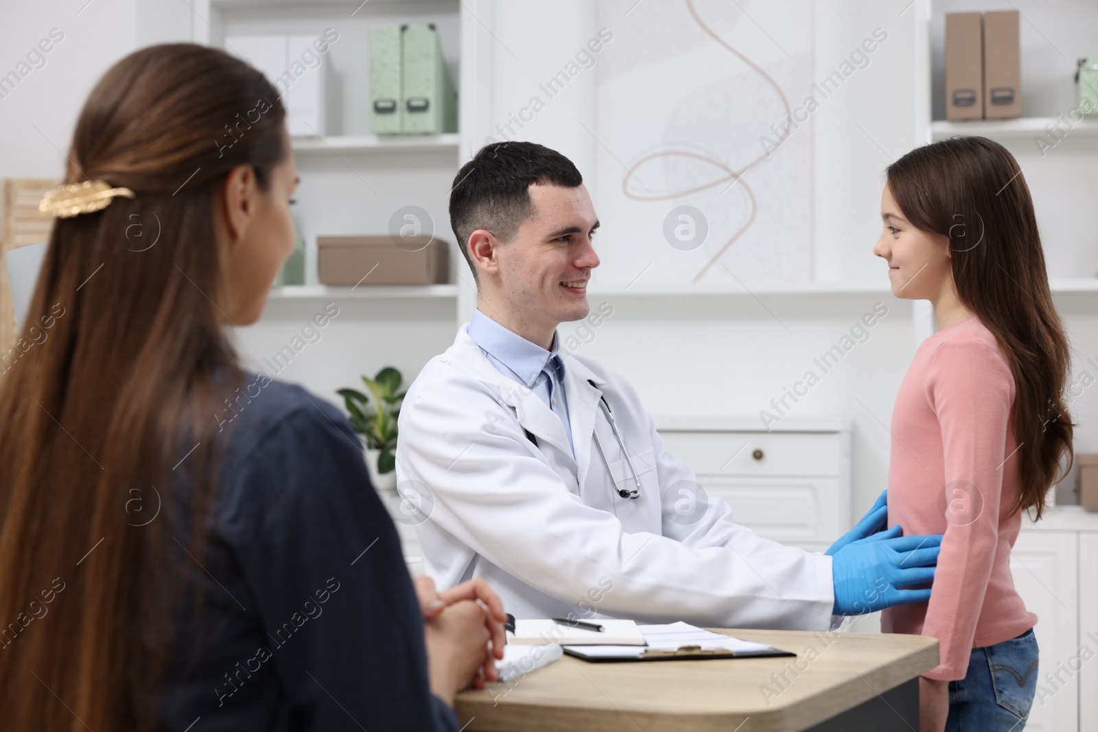 Photo of Gastroenterologist examining girl with stomach ache in clinic