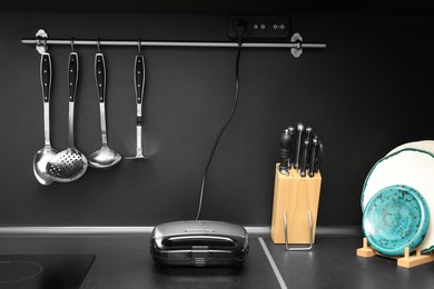 Photo of Sandwich toaster and kitchen utensils on black countertop