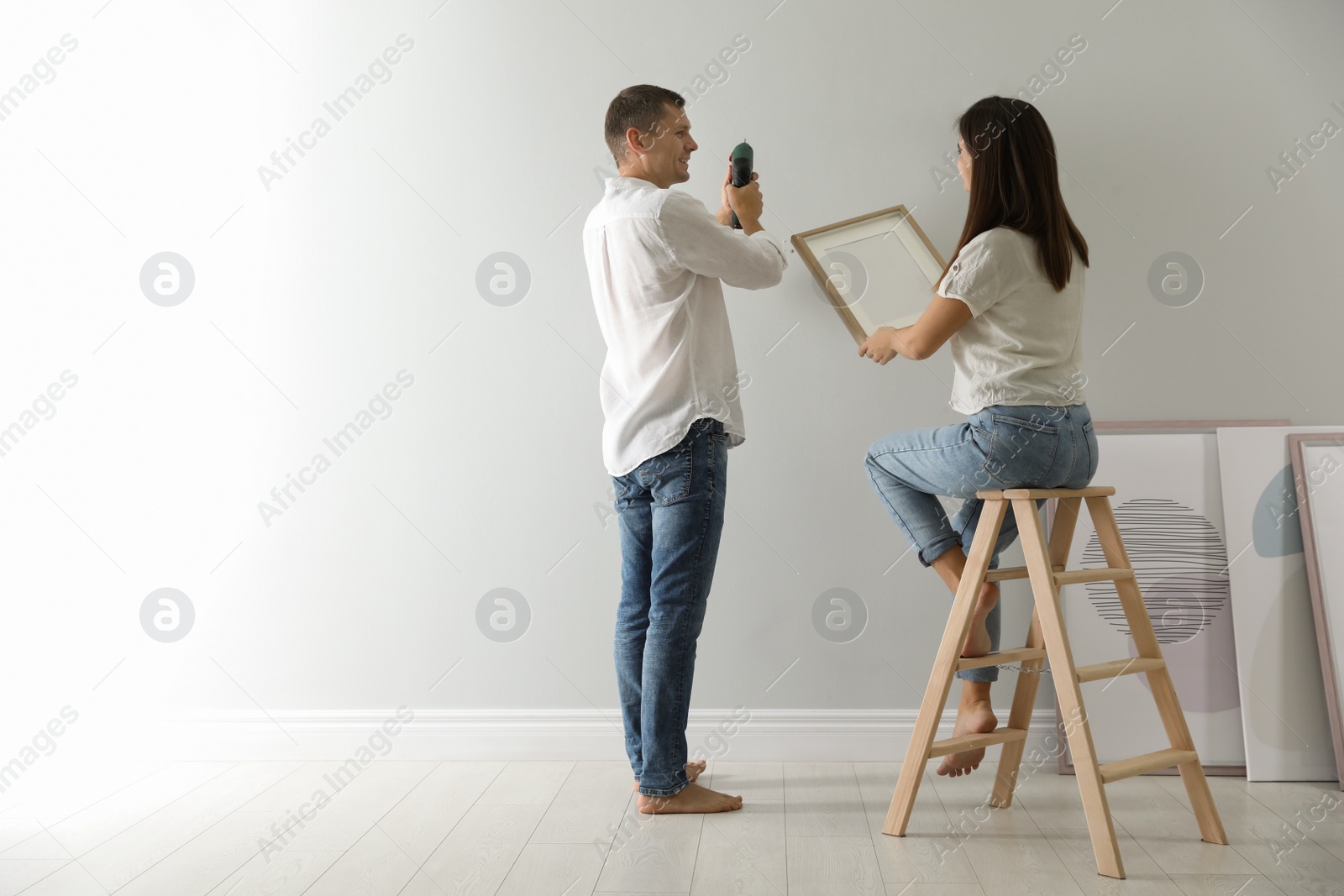 Photo of Couple decorating room with picture together. Interior design