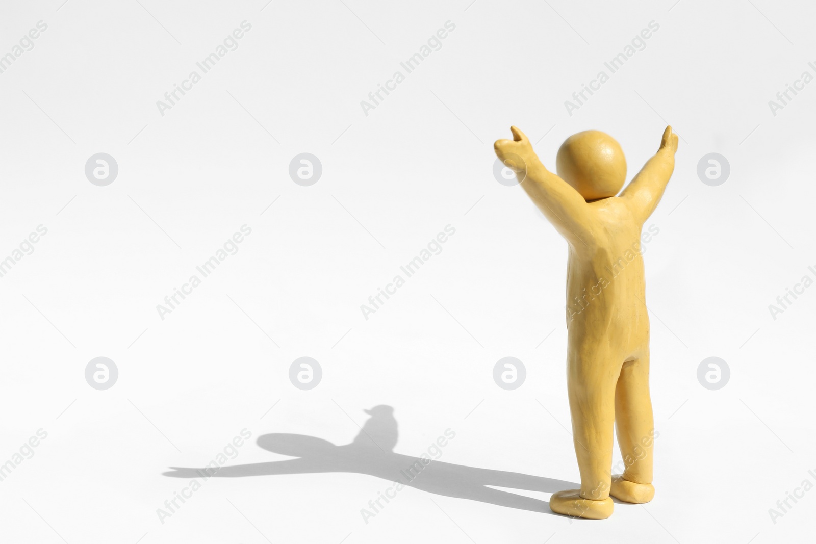 Photo of Human figure with arms wide open made of yellow plasticine on white background