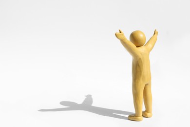 Photo of Human figure with arms wide open made of yellow plasticine on white background