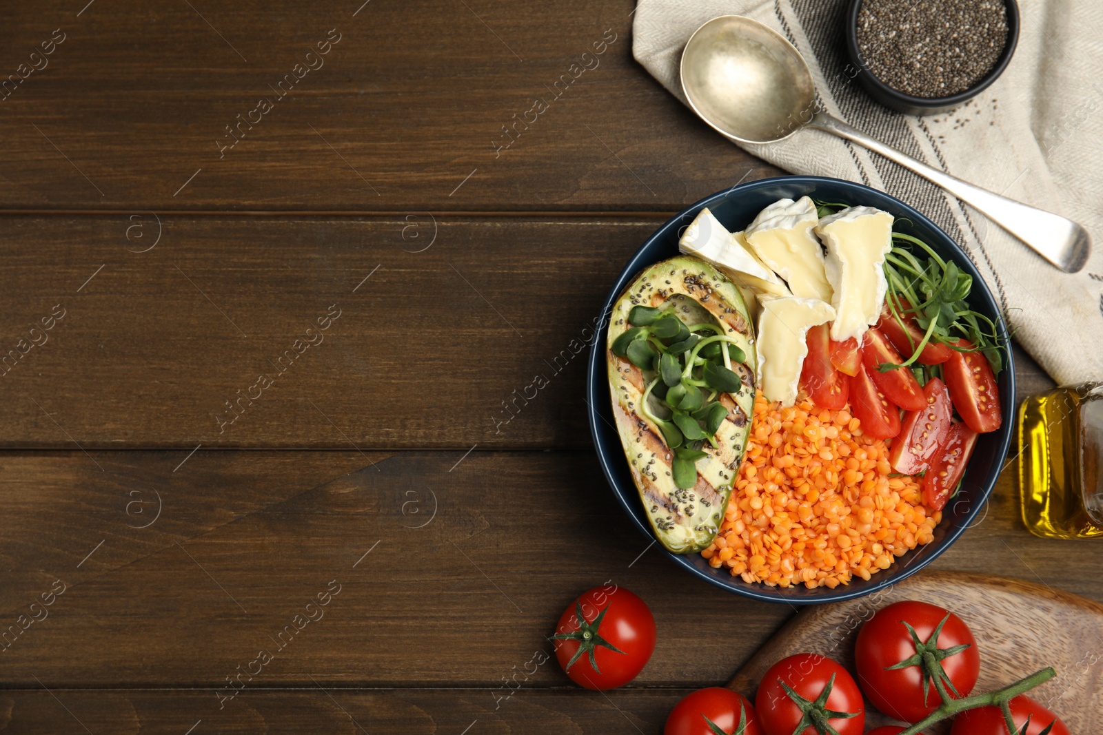 Photo of Delicious lentil bowl with soft cheese, avocado and tomatoes on wooden table, flat lay. Space for text