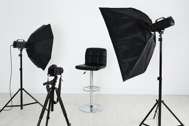 Empty chair in front of camera and professional lighting equipment indoors. Photo studio set