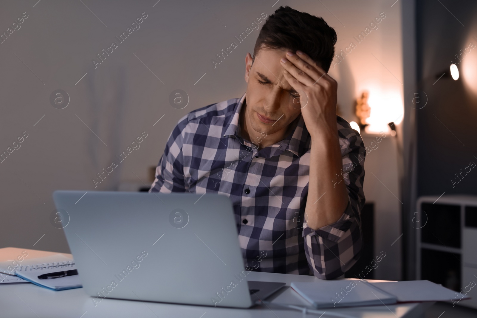 Photo of Overworked man with headache in office