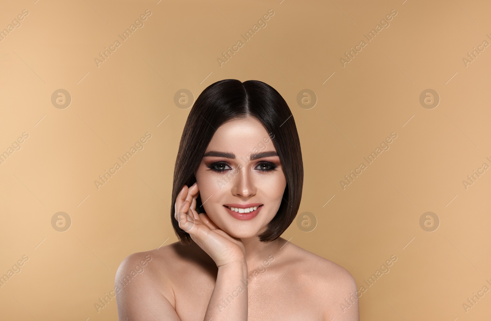 Image of Portrait of pretty young woman with brown hair smiling on beige background