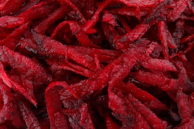 Grated fresh red beet as background, closeup view