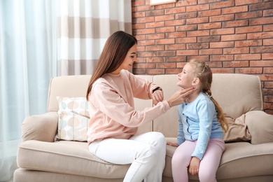 Photo of Young woman checking little girl's pulse with fingers at home