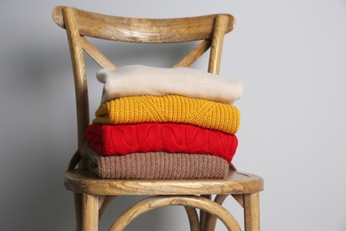 Photo of Stack of folded knitted sweaters on wooden chair