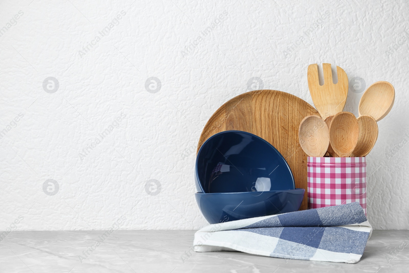 Photo of Set of kitchen utensils in stand on stone table near light wall. Space for text