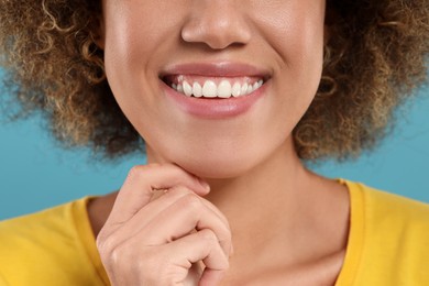 Photo of Woman with clean teeth smiling on light blue background, closeup