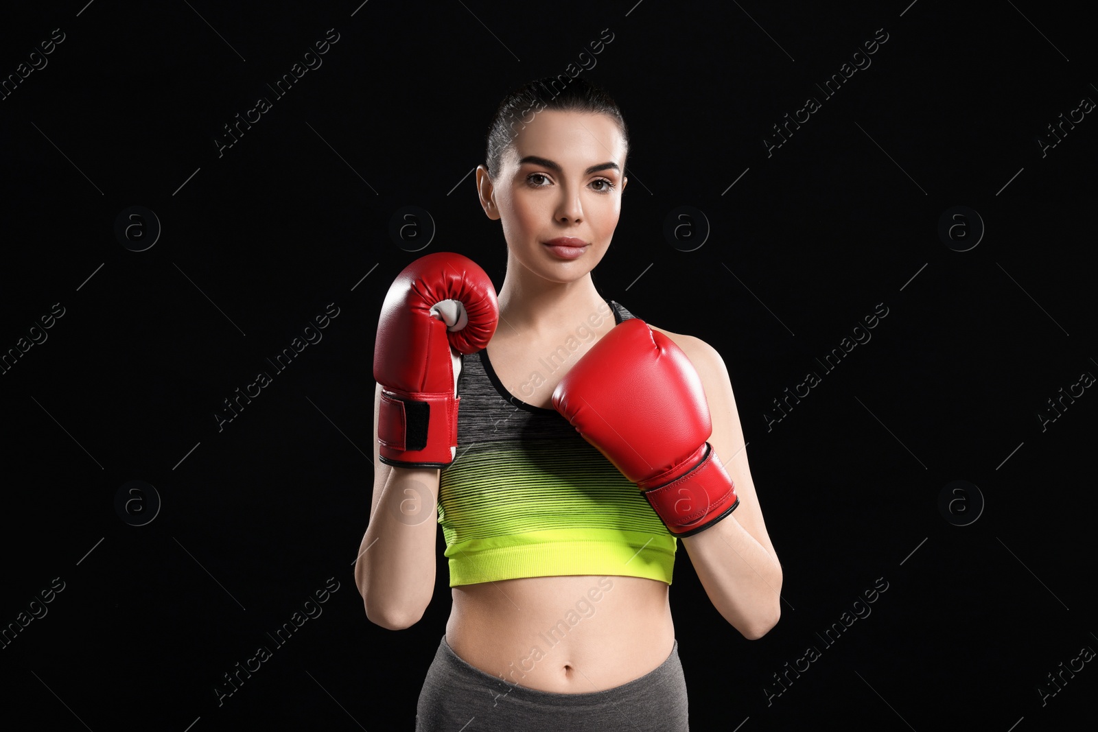 Photo of Portrait of beautiful woman in boxing gloves on black background