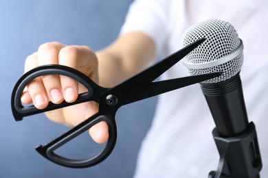 Photo of Woman making ASMR sounds with microphone and scissors on blue background, closeup