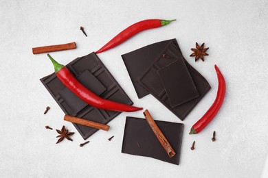 Photo of Delicious chocolate, fresh red chili peppers and spices on white table, flat lay