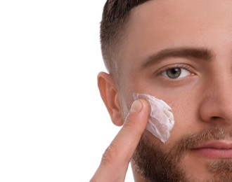 Photo of Handsome man applying cream onto his face on white background, closeup