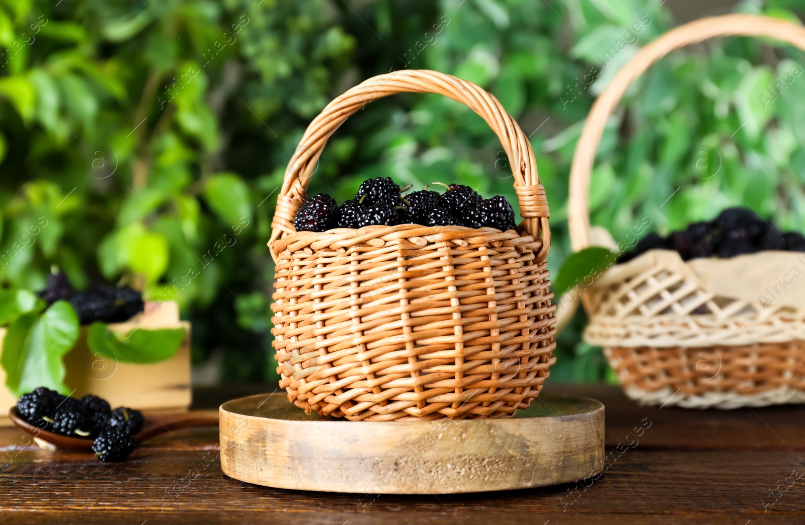 Photo of Fresh ripe black mulberries on wooden table against blurred background